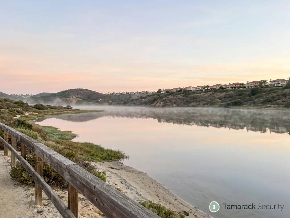 Calm coastal lagoon at dawn with hillside homes above it