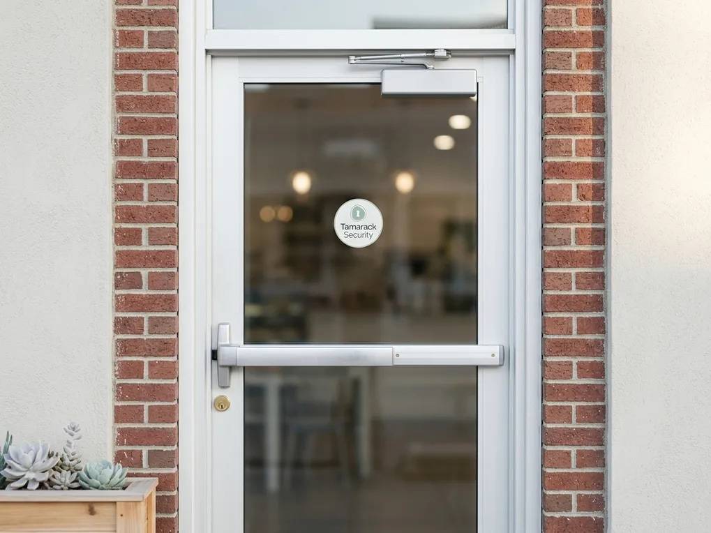 Glass storefront door with a push-bar exit device and door closer on a brick facade